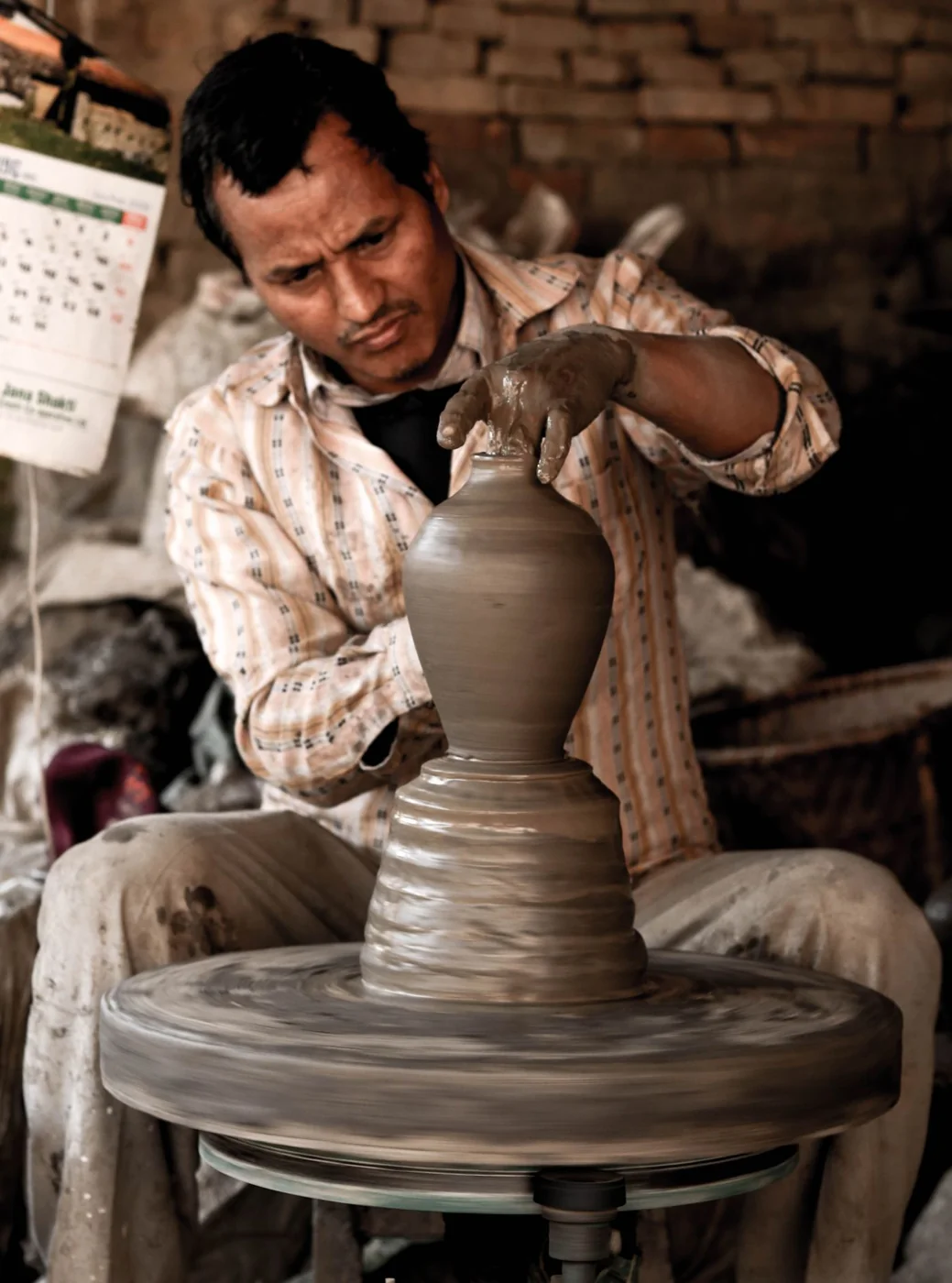 A Nepalese pottery host shaping a clay vessel